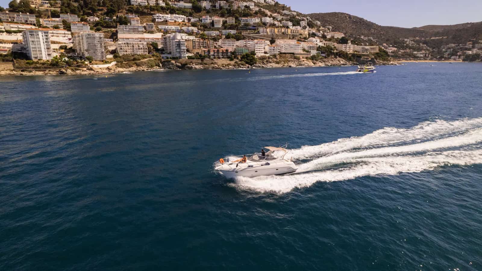 Boat trip sailing in front of the Roses seafront promenade, Costa Brava